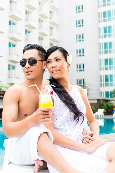 Asian Friends sitting by hotel swimming pool — Stock Photo, Image