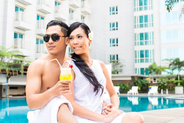 Asian Friends sitting by hotel swimming pool — Stock Photo, Image