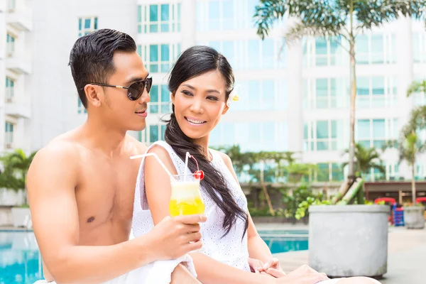 Asian Friends sitting by hotel swimming pool — Stock Photo, Image