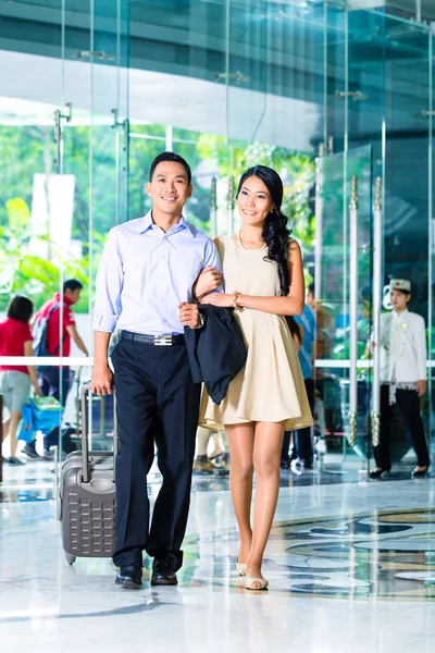 Asian couple arriving in hotel lobby — Stock Fotó