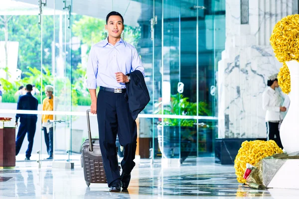 Asiatiska man dra resväska i hotellets lobby — Stockfoto