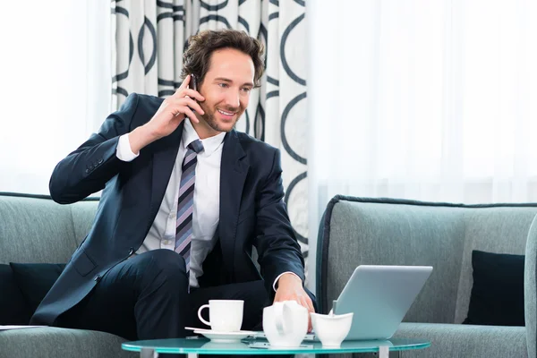 Affärsman i affärshotell är på telefon — Stockfoto