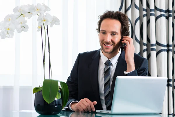 Affärsman i hotel är på telefonen — Stockfoto