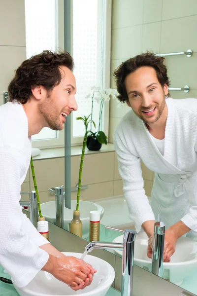 Jonge man in badjas in hotel badkamer — Stockfoto