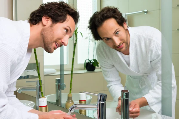 Young man in bathrobe in hotel bathroom — Stock Photo, Image