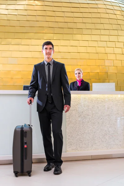 Man departing on business trip at hotel reception — Stock Photo, Image