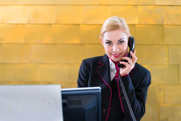 Hotel receptionist with phone on front desk — Stock Photo, Image