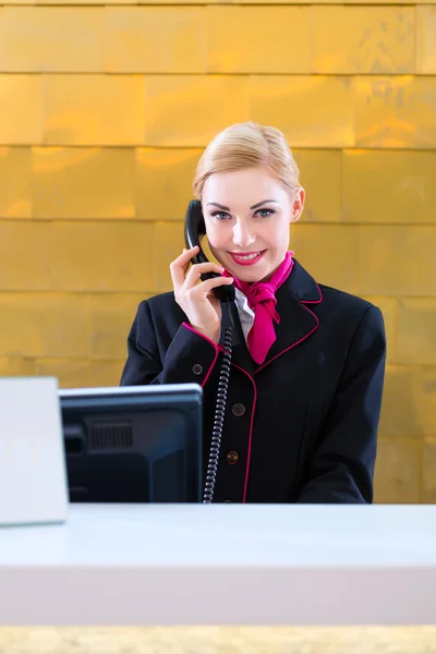 Hotel receptionist with phone on front desk — Stock Photo, Image