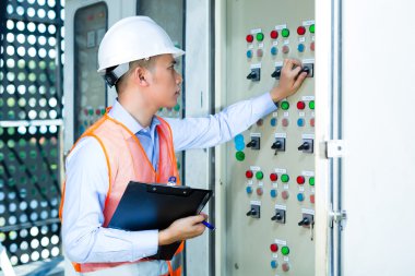Asian technician at panel on construction site
