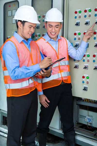 Asian technicians at panel on construction site — Stockfoto