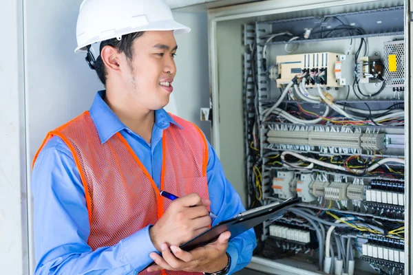 Asian Electrician at panel on construction site — Φωτογραφία Αρχείου