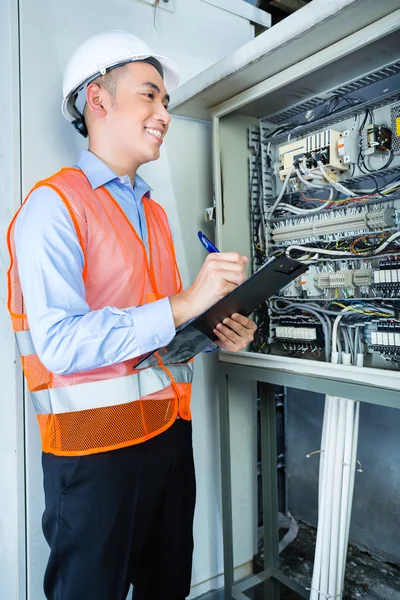 Asian Electrician at panel on construction site — стокове фото