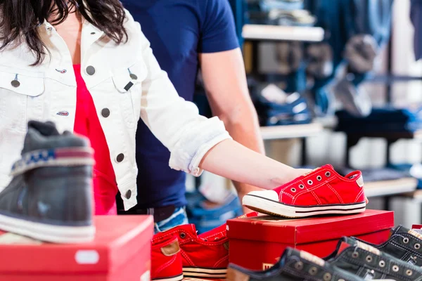 Kvinnan som köper sneakers skor i butik — Stockfoto