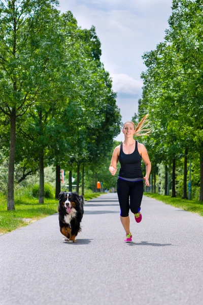 Young woman running with dog in park — Stock Photo, Image