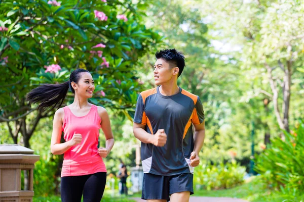 Chinese man and woman jogging in city park — Stock Photo, Image