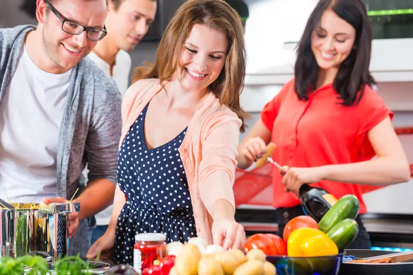 Friends cooking pasta and meat in domestic kitchen — Stock Photo, Image