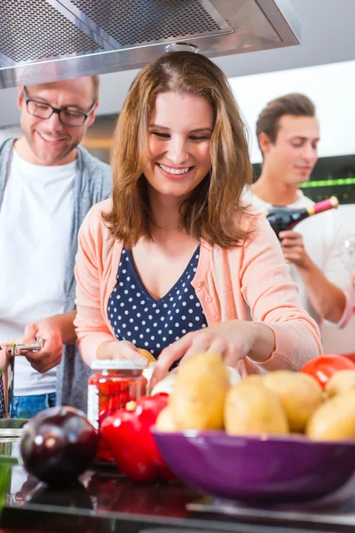 Amigos cocinando pasta y carne en la cocina doméstica —  Fotos de Stock