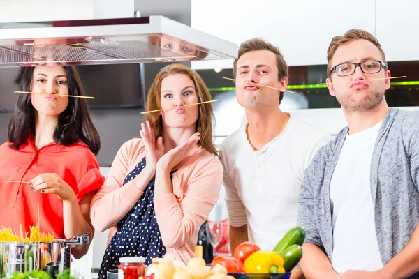 Amigos cocinando pasta y carne en la cocina doméstica — Foto de Stock