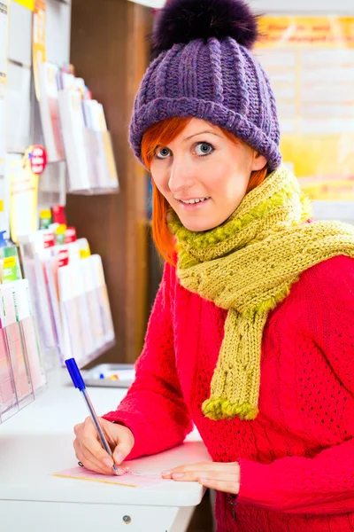 woman in Lotto shop playing ticket