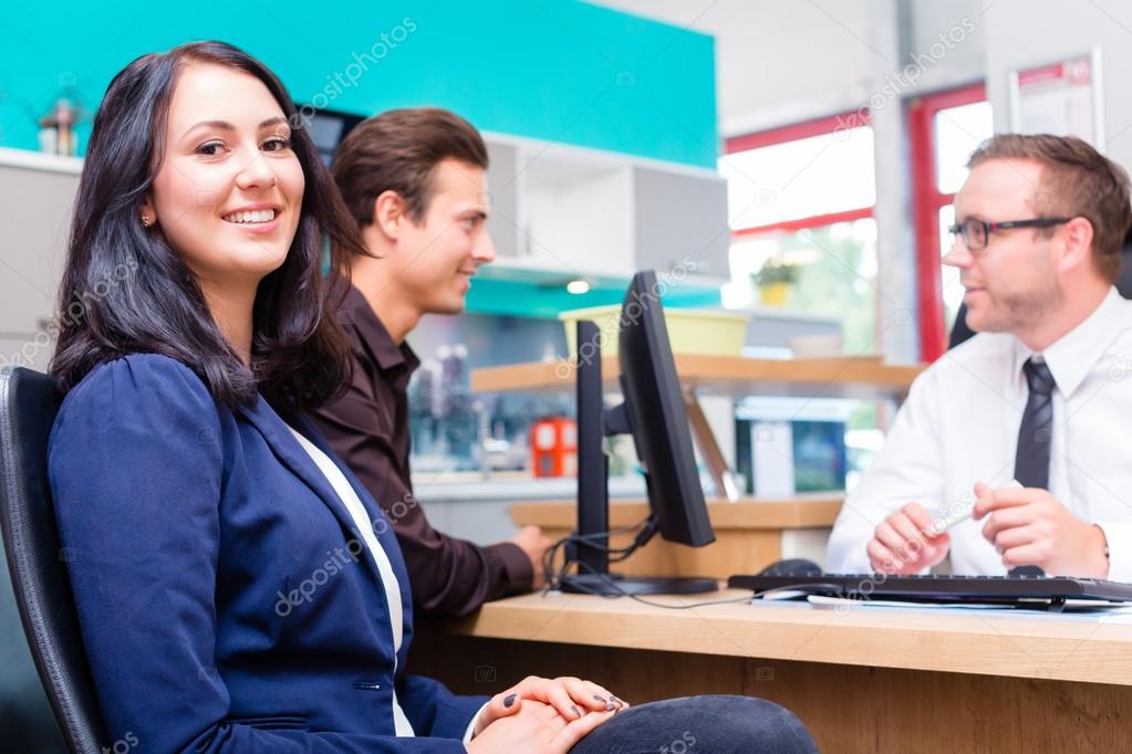 Couple planning kitchen with salesman in furniture store