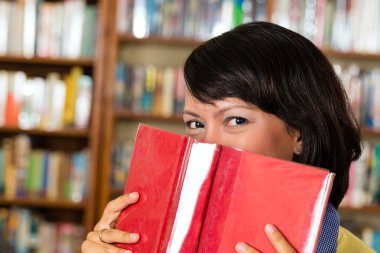 Kitaplığındaki kitap okuyarak Asyalı kız