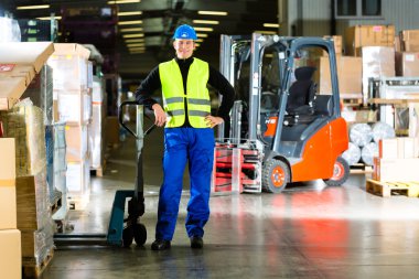 Warehouseman in protective vest holds a mover