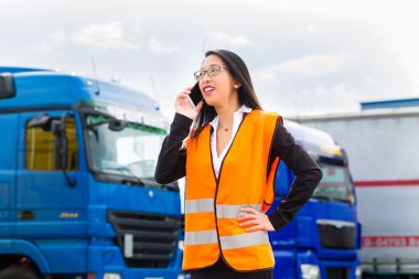 Female forwarder in front of trucks on a depot clipart