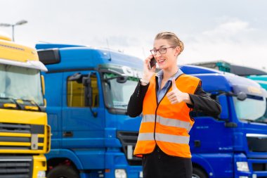 Female forwarder in front of trucks on a depot clipart