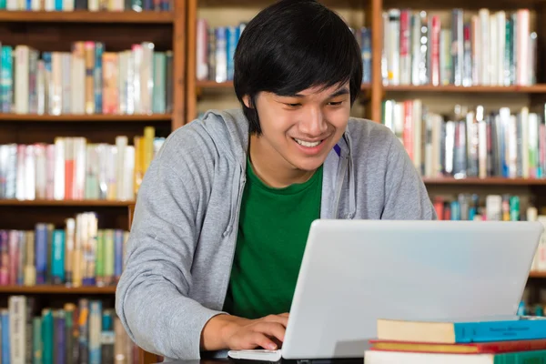 Asiático homem na biblioteca com laptop — Fotografia de Stock
