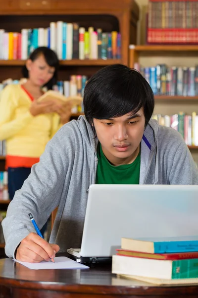 Man i biblioteket med laptop — Stockfoto