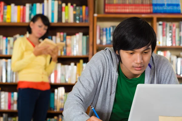 Homem na biblioteca com laptop — Fotografia de Stock