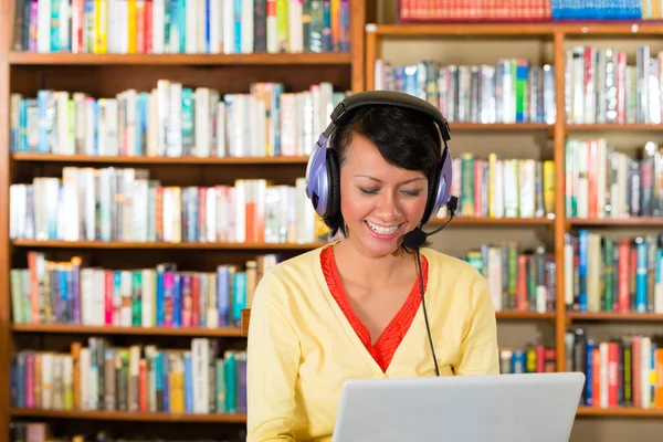 Κορίτσι στη βιβλιοθήκη με φορητό υπολογιστή και ακουστικά — Φωτογραφία Αρχείου