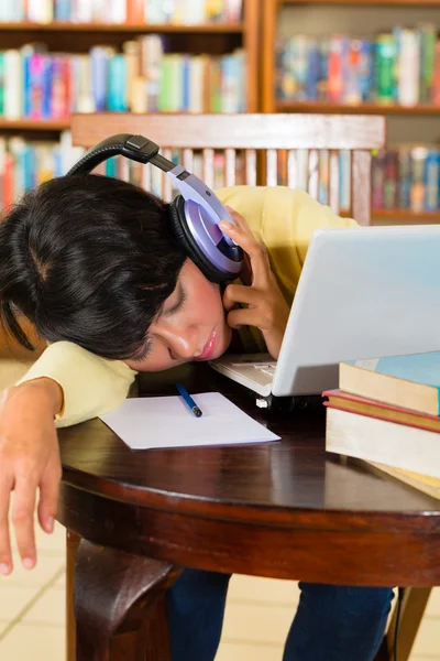 Meisje in bibliotheek met laptop en hoofdtelefoon — Stockfoto