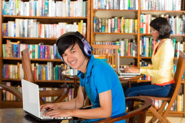 Estudante em biblioteca com laptop — Fotografia de Stock