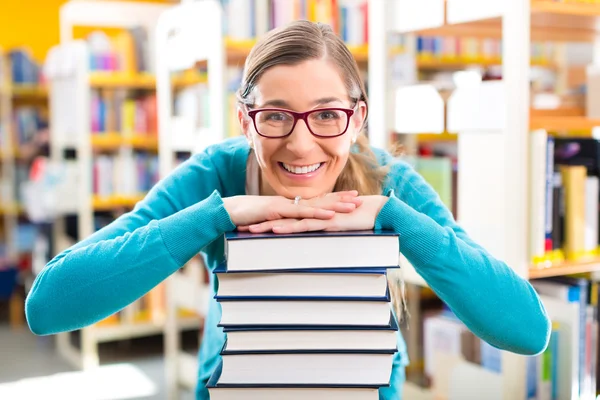 Студент з купою книг навчання в бібліотеці — стокове фото