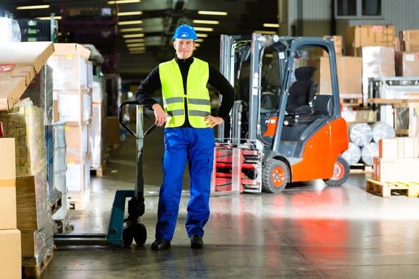 Warehouseman in protective vest holds a mover — Stock Photo, Image