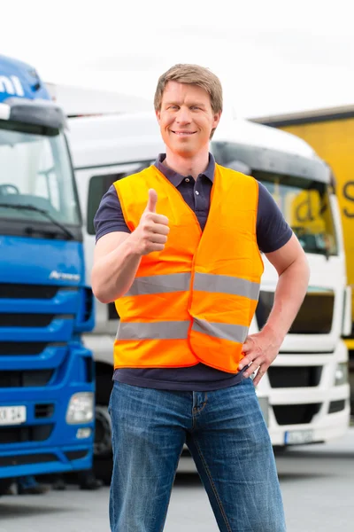 Forwarder or driver in front of trucks in depot — Zdjęcie stockowe