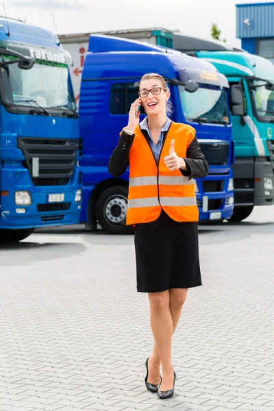 Женщина-экспедитор перед грузовиками на складе — стоковое фото
