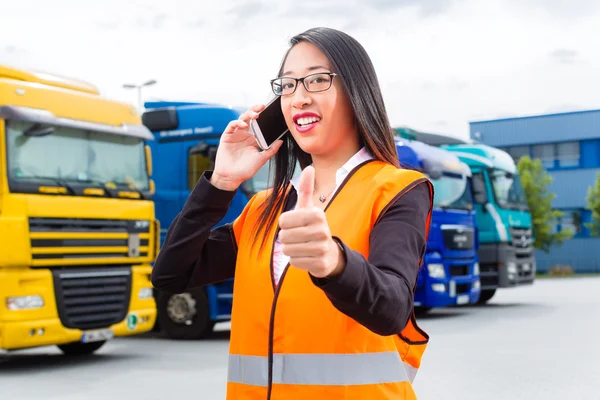 Forwarder feminino na frente de caminhões em um depósito — Fotografia de Stock