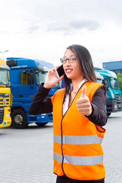 Forwarder feminino na frente de caminhões em um depósito — Fotografia de Stock