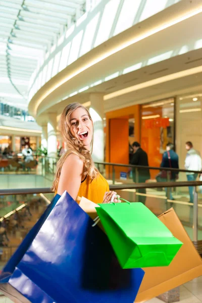 Ung kvinne som handler på kjøpesenteret med poser – stockfoto