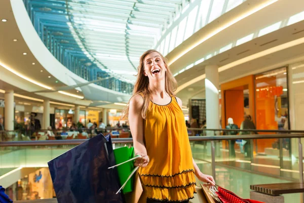 Mujer joven de compras en el centro comercial con bolsas —  Fotos de Stock