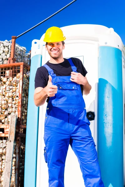 Builder using mobile toilet on site — Stock Photo, Image