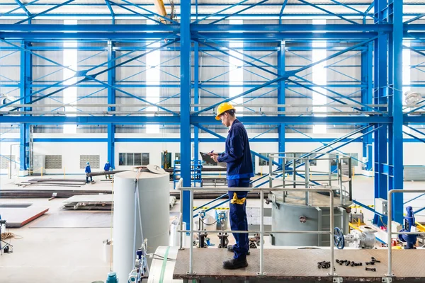 Worker in large metal workshop checking work — Stock Photo, Image