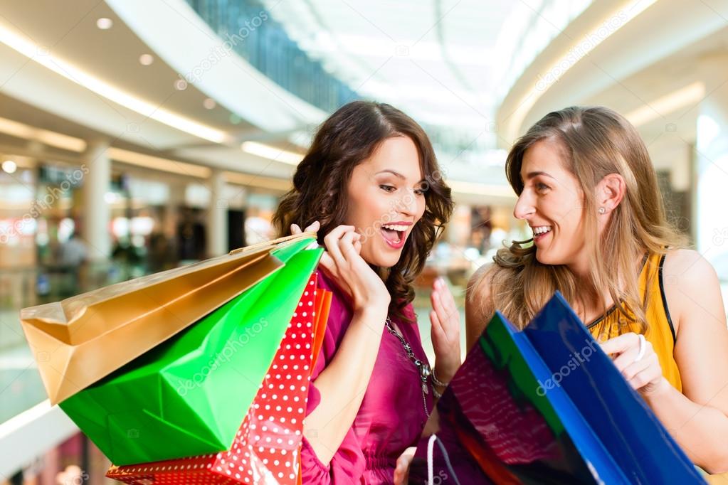 Two girls shopping in mall looking in bags