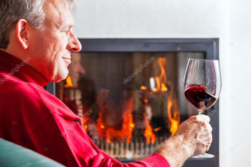 Man drinking red wine on fireplace