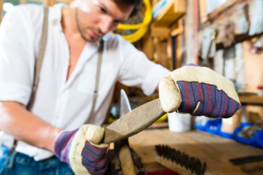 Young man sharpening tools in mountains hut