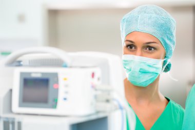 Doktor ya da hemşire kalp monitörüyle ameliyathanede.