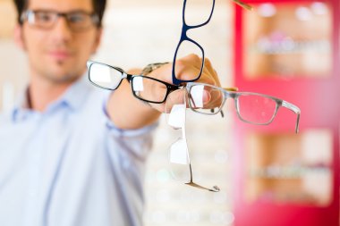 Young man at optician with glasses clipart