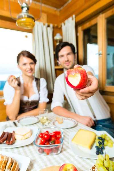 Young couple in mountain chalet eating — Φωτογραφία Αρχείου